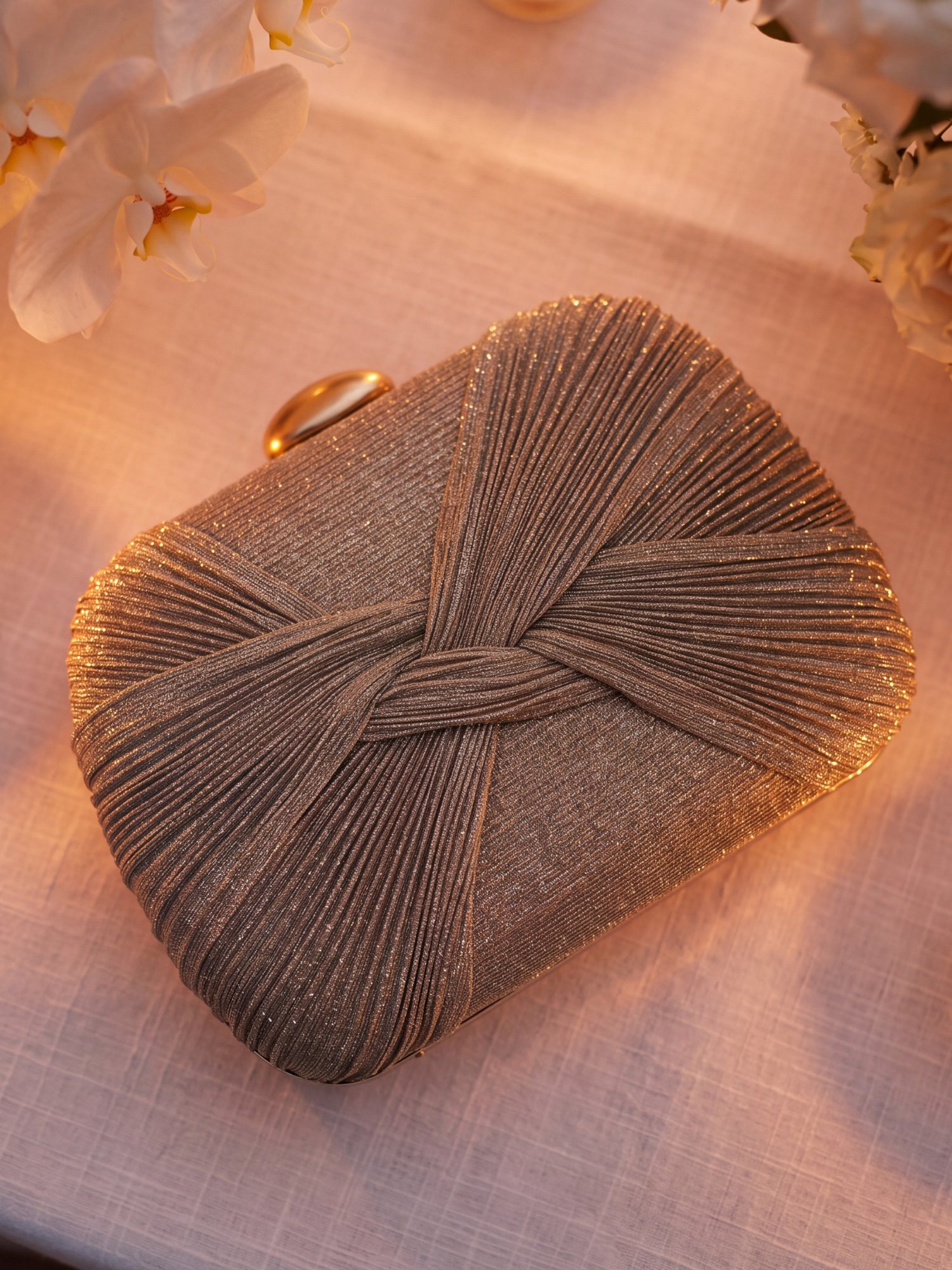 Gold pleated clutch on a candlelit table