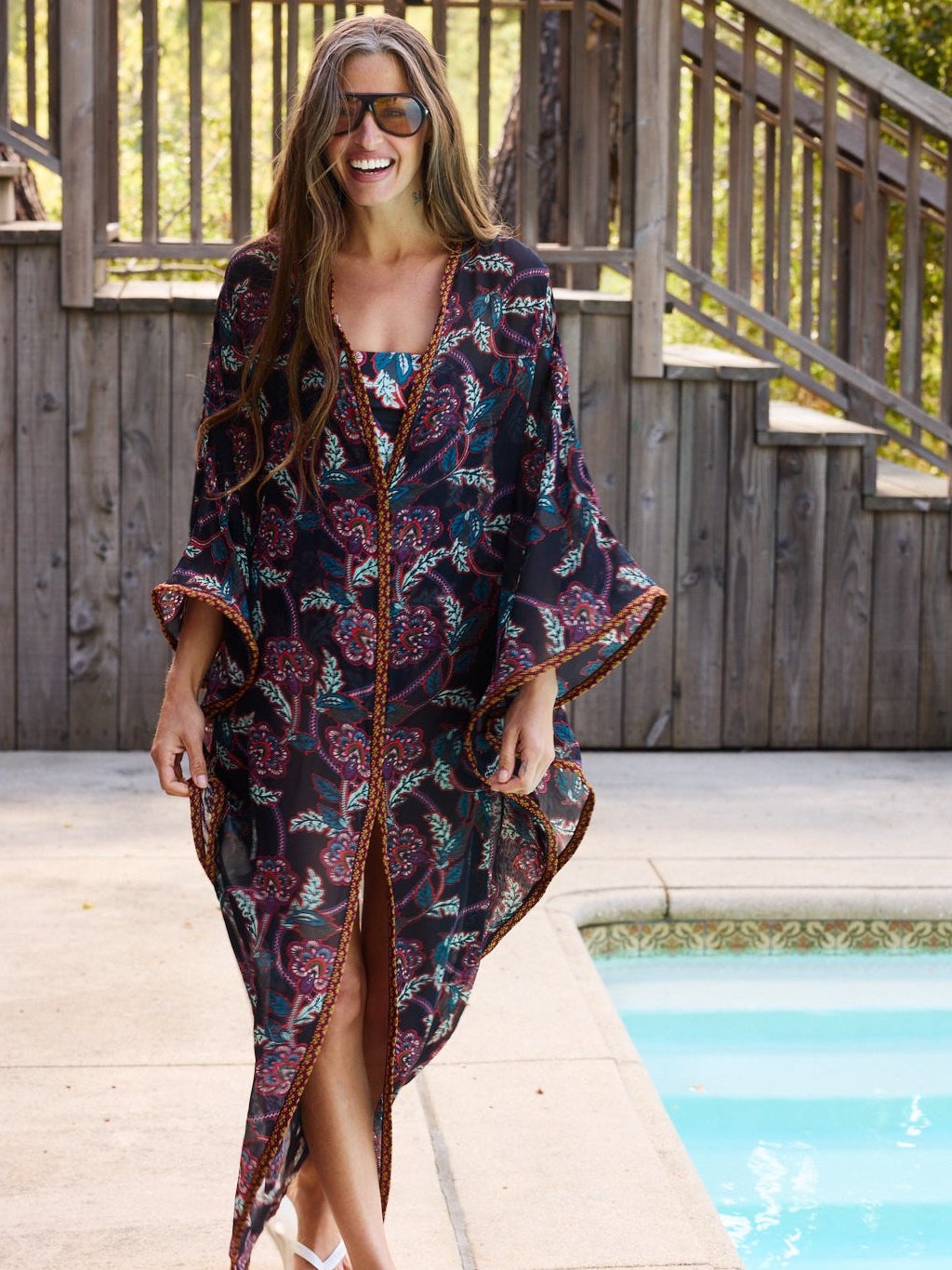 Model in a dark floral kaftan beside a pool
