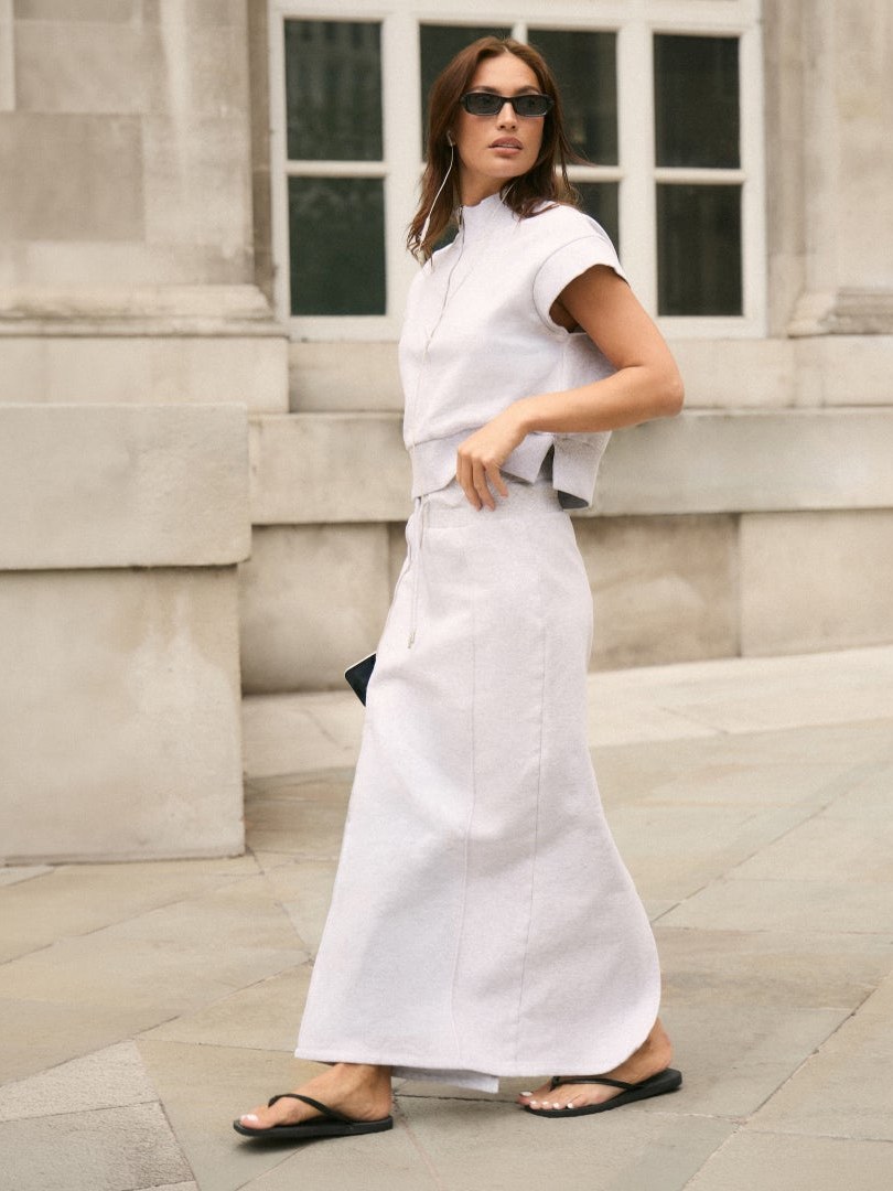 Model in a white knit co-ord on a city sidewalk