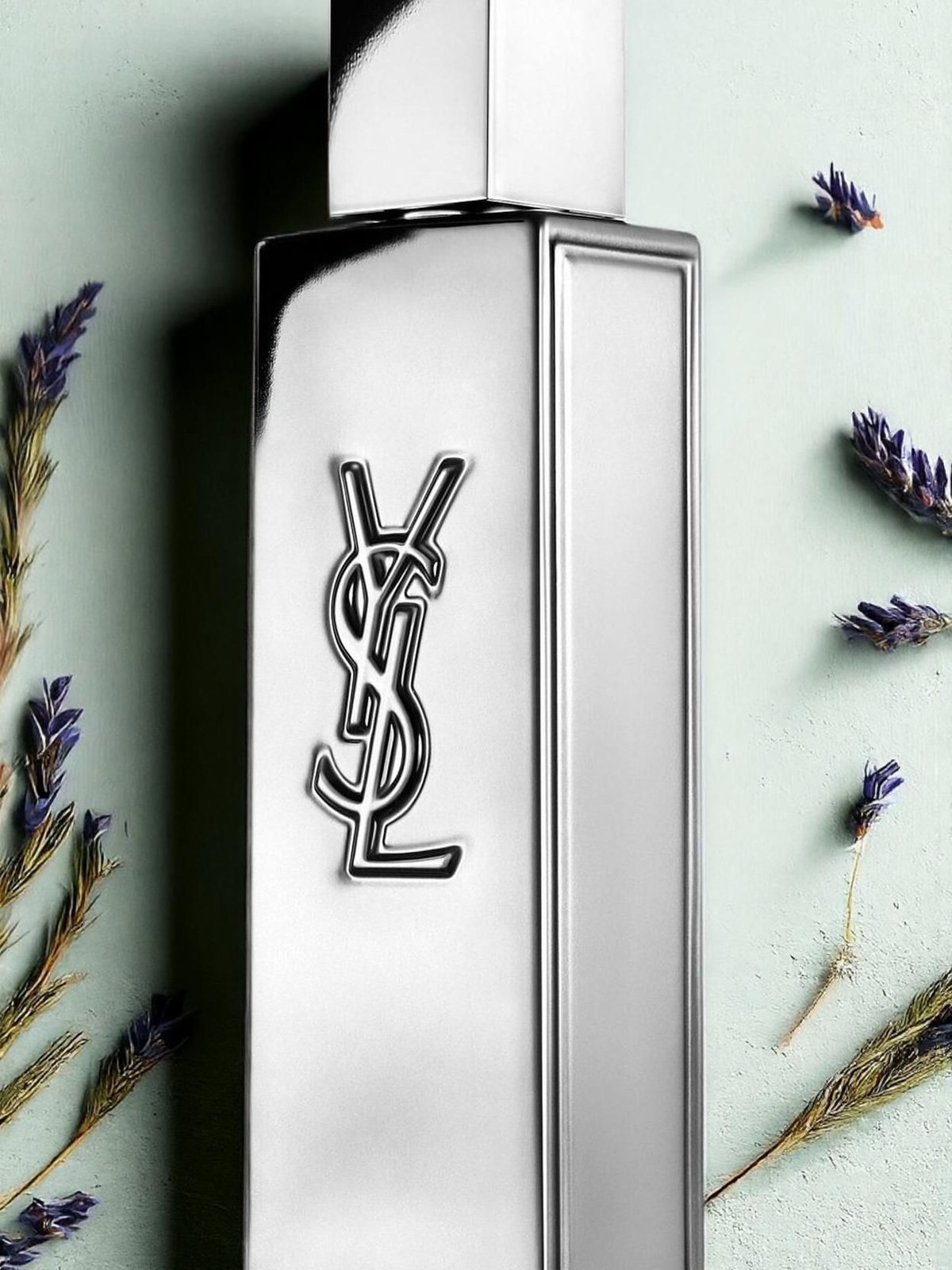 Silver YSL fragrance bottle with YSL logo beside dried lavender sprigs