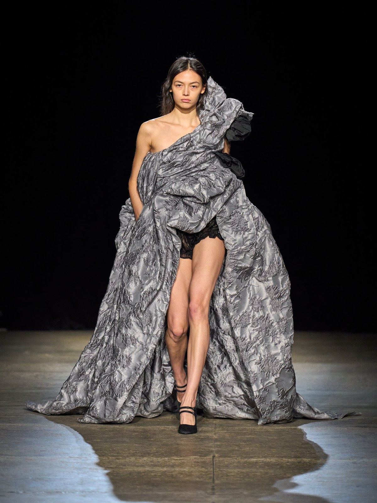 Model in a sculptural silver-gray gown on the AKNVAS Fall 2026 runway