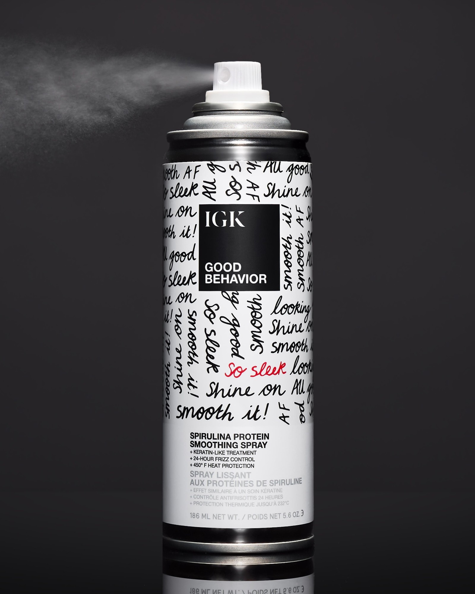 Black IGK Good Behavior Spirulina Protein Smoothing Spray can spraying a mist against a dark background