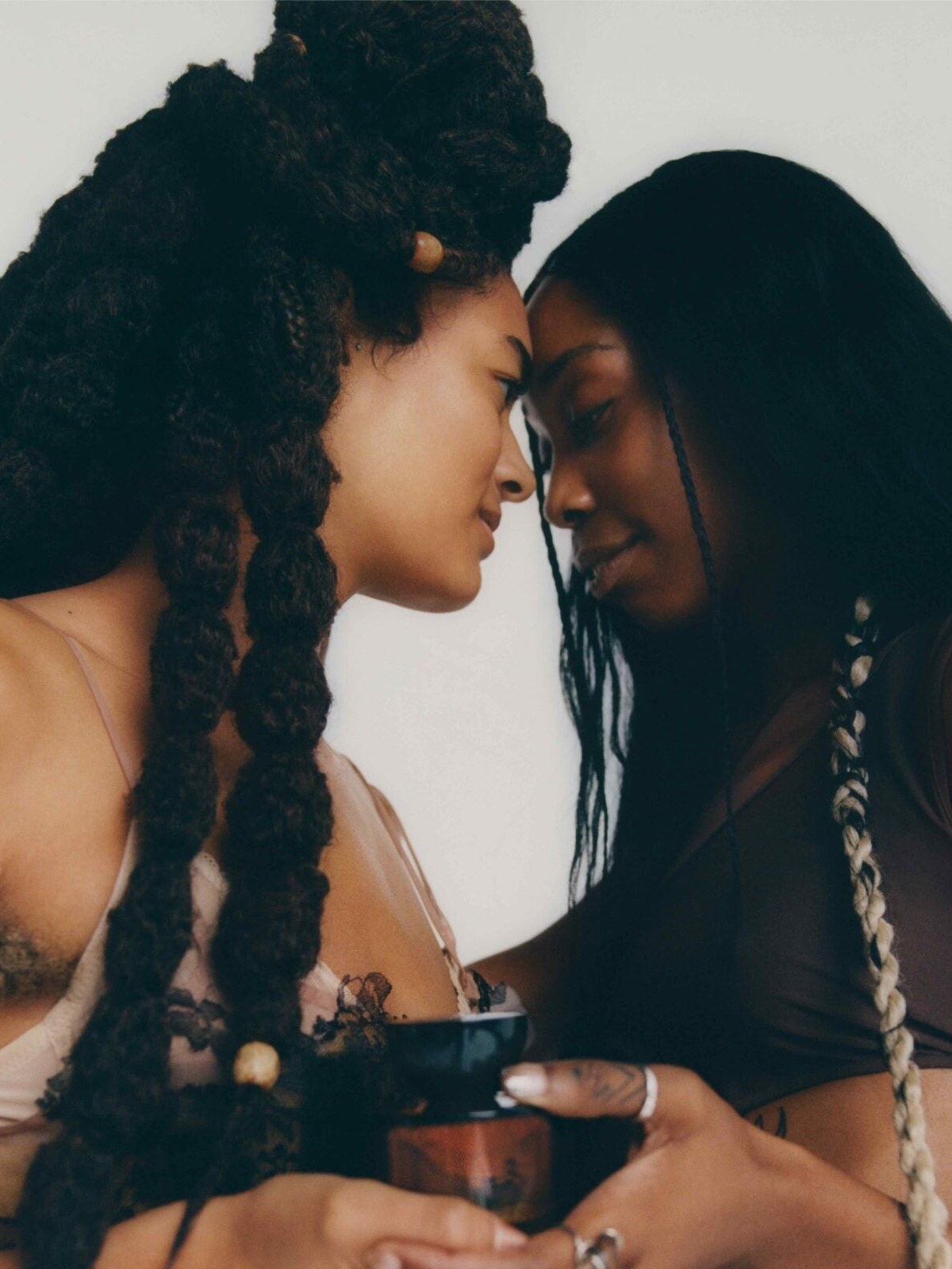 Two models meeting forehead to forehead with perfume bottles