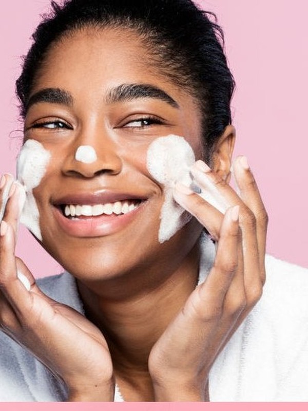 Woman massaging foamy cleanser onto her cheeks