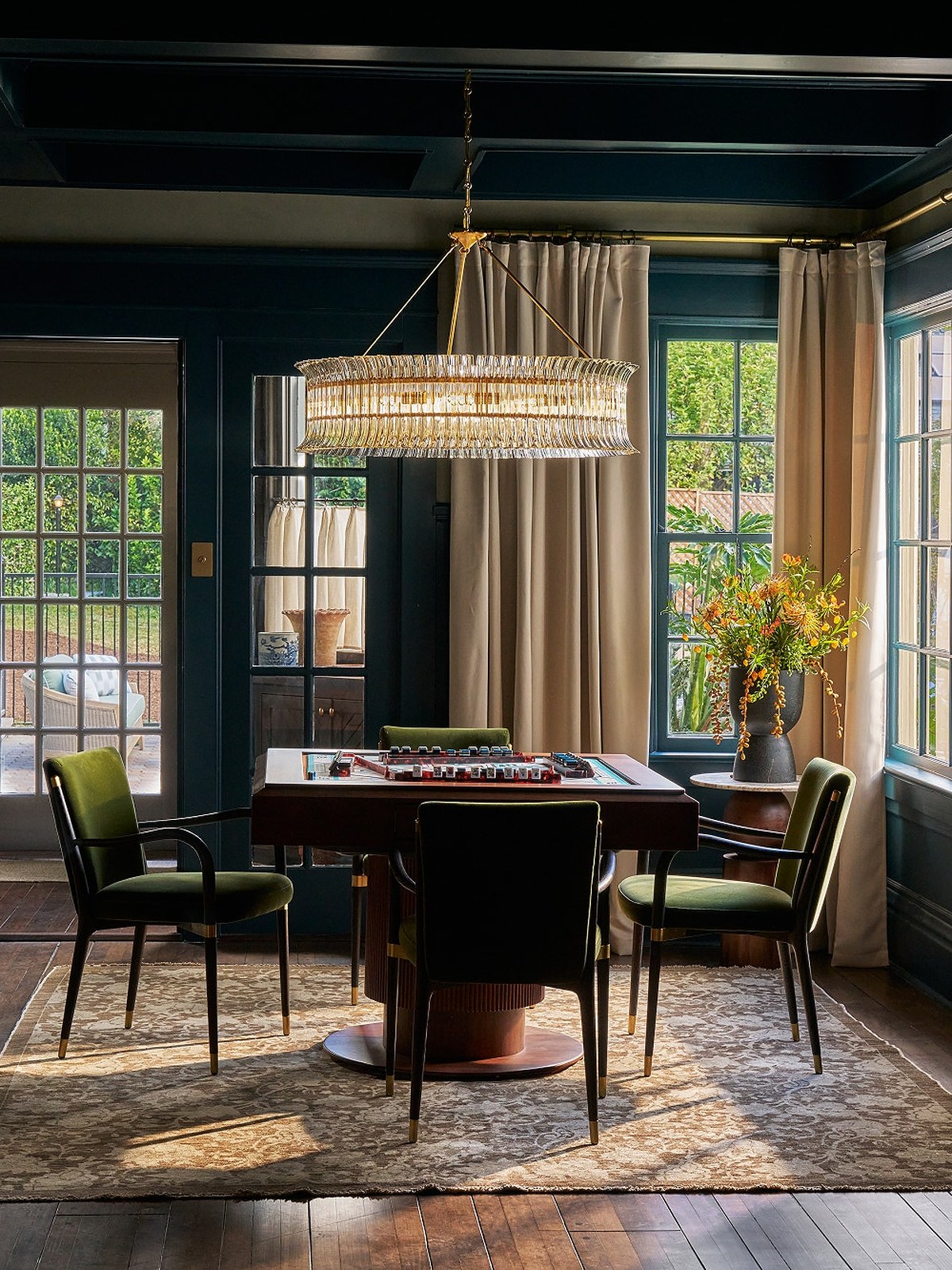 Dining room with a long crystal rod pendant over a round table and teal walls