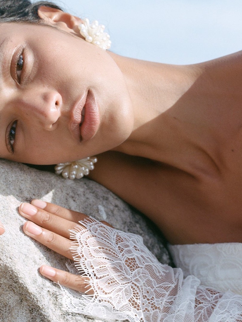Bride in lace detail resting against a soft backdrop