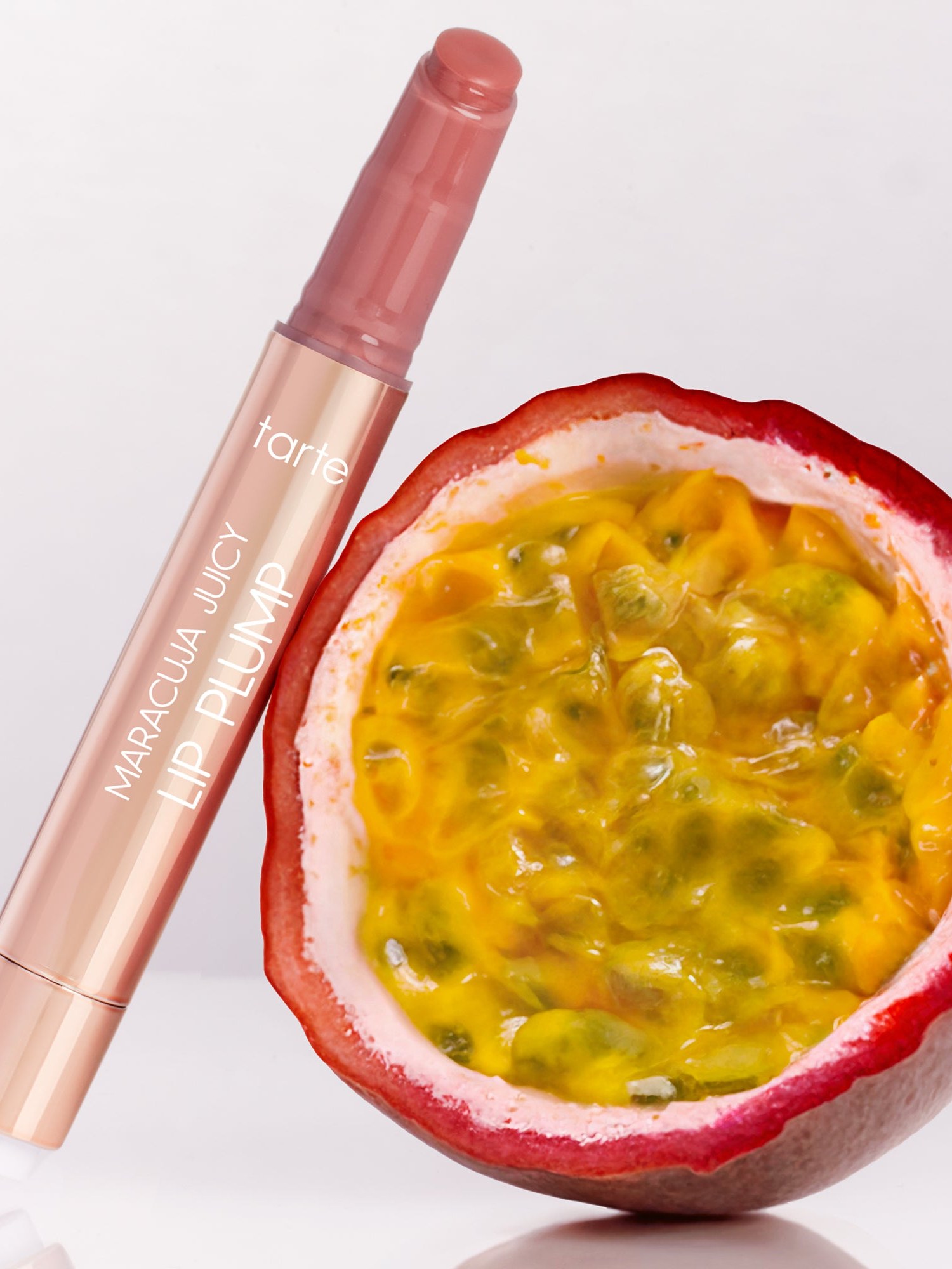 Tarte Maracuja Juicy Lip Plump beside a halved passion fruit